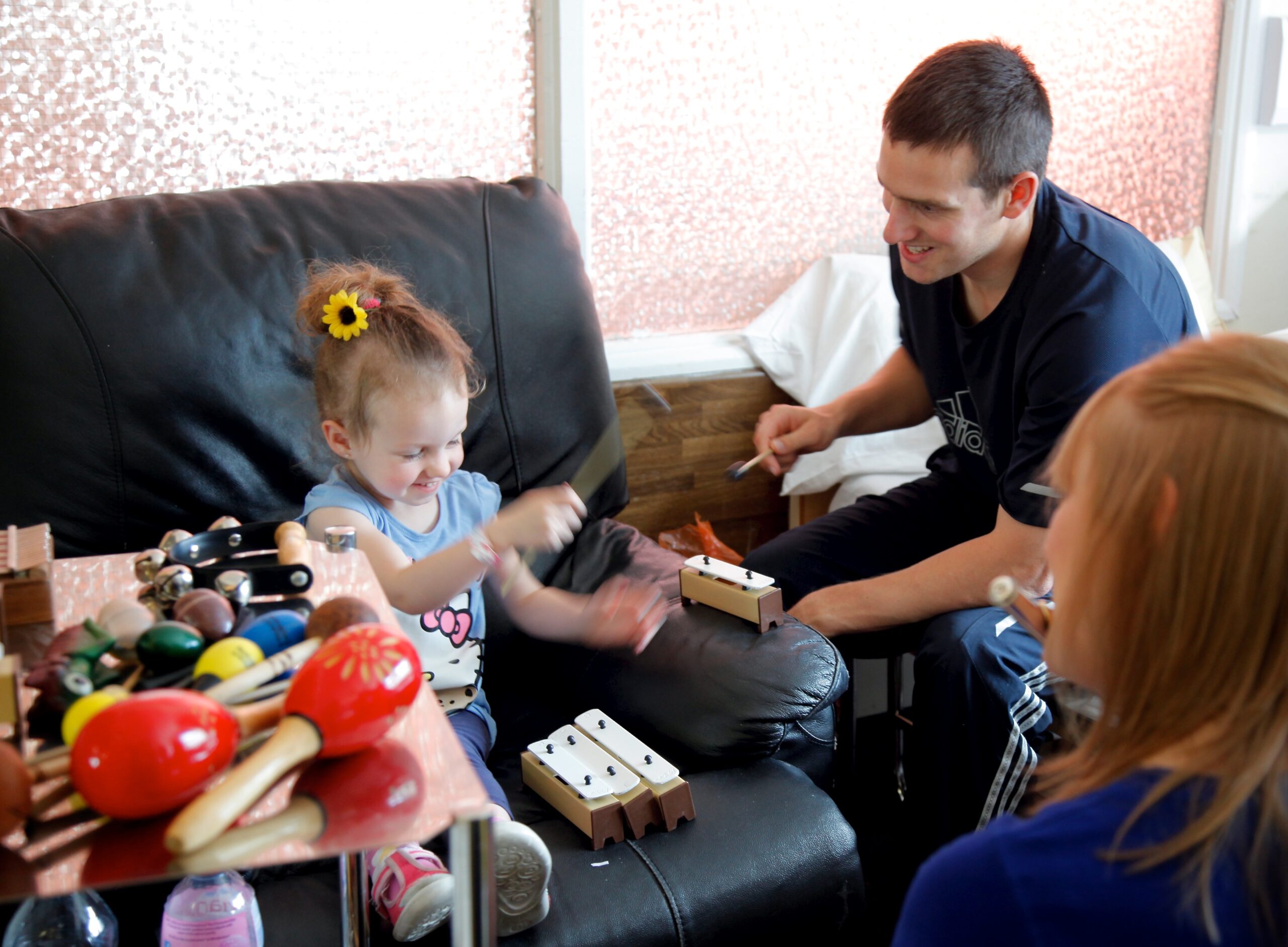 Image shown: Scales & Tales musician Caoimhe Conlon with a little girl and her father